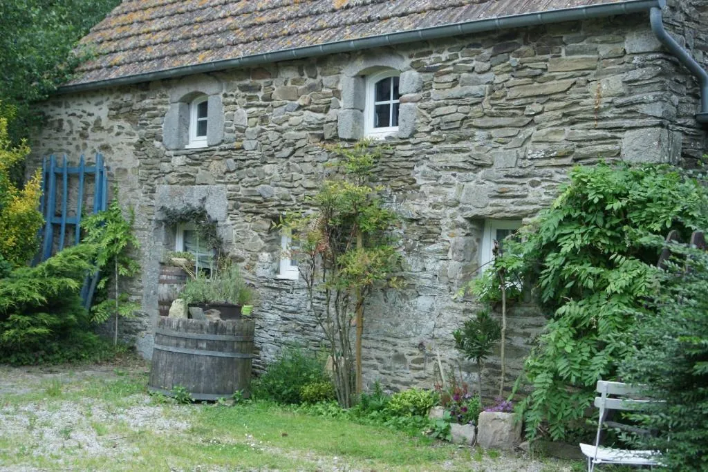 La façade en pierre du gîte et son tonneau fleuri